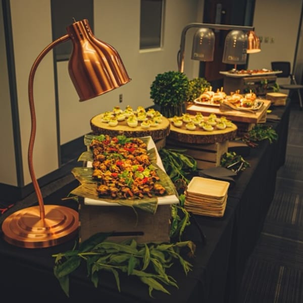 A buffet table with various appetizers, including deviled eggs, sliders, and a dish with green herbs.