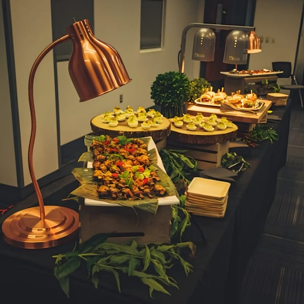 A buffet table with various appetizers, including deviled eggs, mini sliders, and fried chicken.
